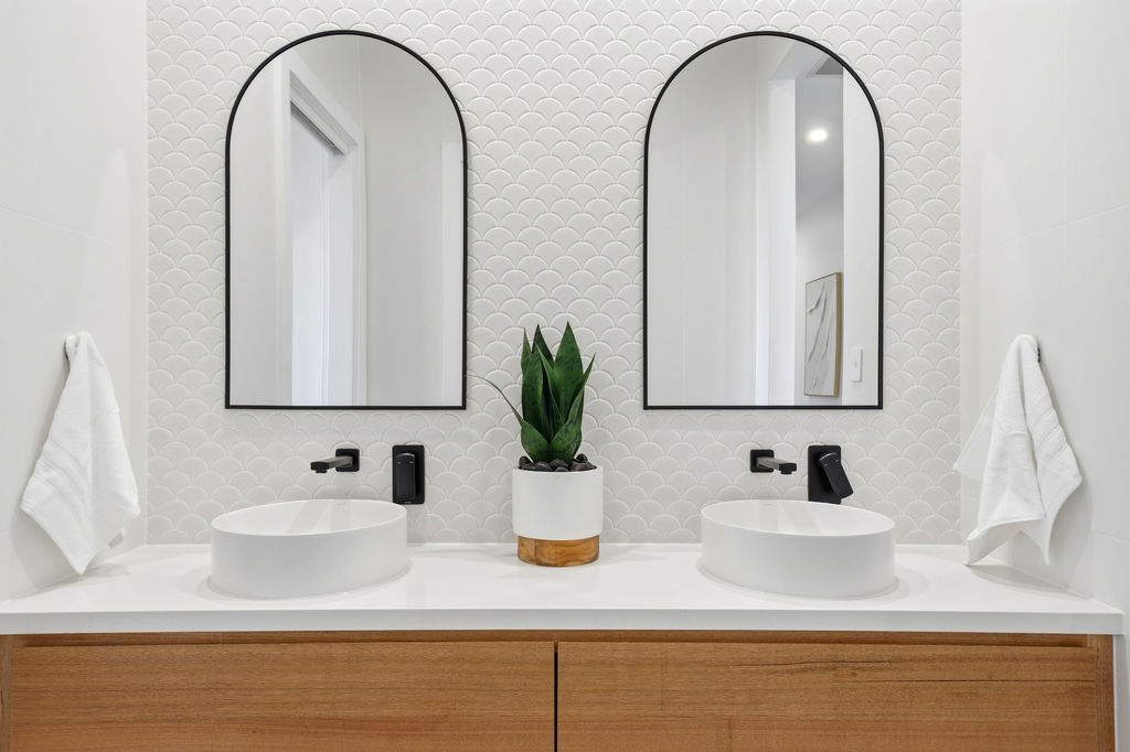 Double vanity with arch mirrors and fish scale tile